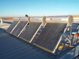 Sistema de calentadores solares instalados en un techo metálico, compuesto por tubos de vidrio al vacío y tanques cilíndricos con el logo de la empresa 'LatuSolar'. El fondo muestra un paisaje despejado con cielo azul y una persona trabajando cerca del equipo.
